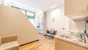 A modern kitchen with a sink, countertop, and a dining area with chairs and a table.