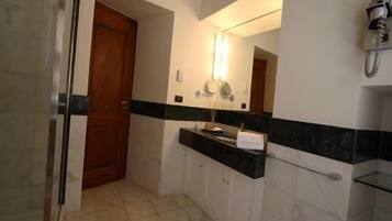 Un baño con puerta de madera, un espejo con luz, un lavabo con toalla y una cabina de ducha con paredes de cristal.
