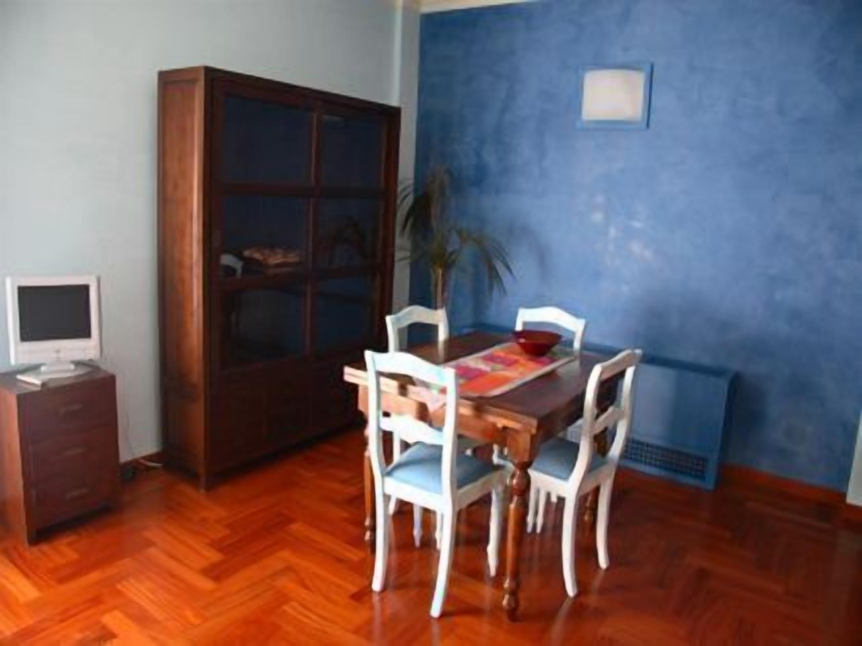 Ein Essbereich mit Holztisch und -stühlen, einem Schrank und einem Fernseher auf einem Standfuß.