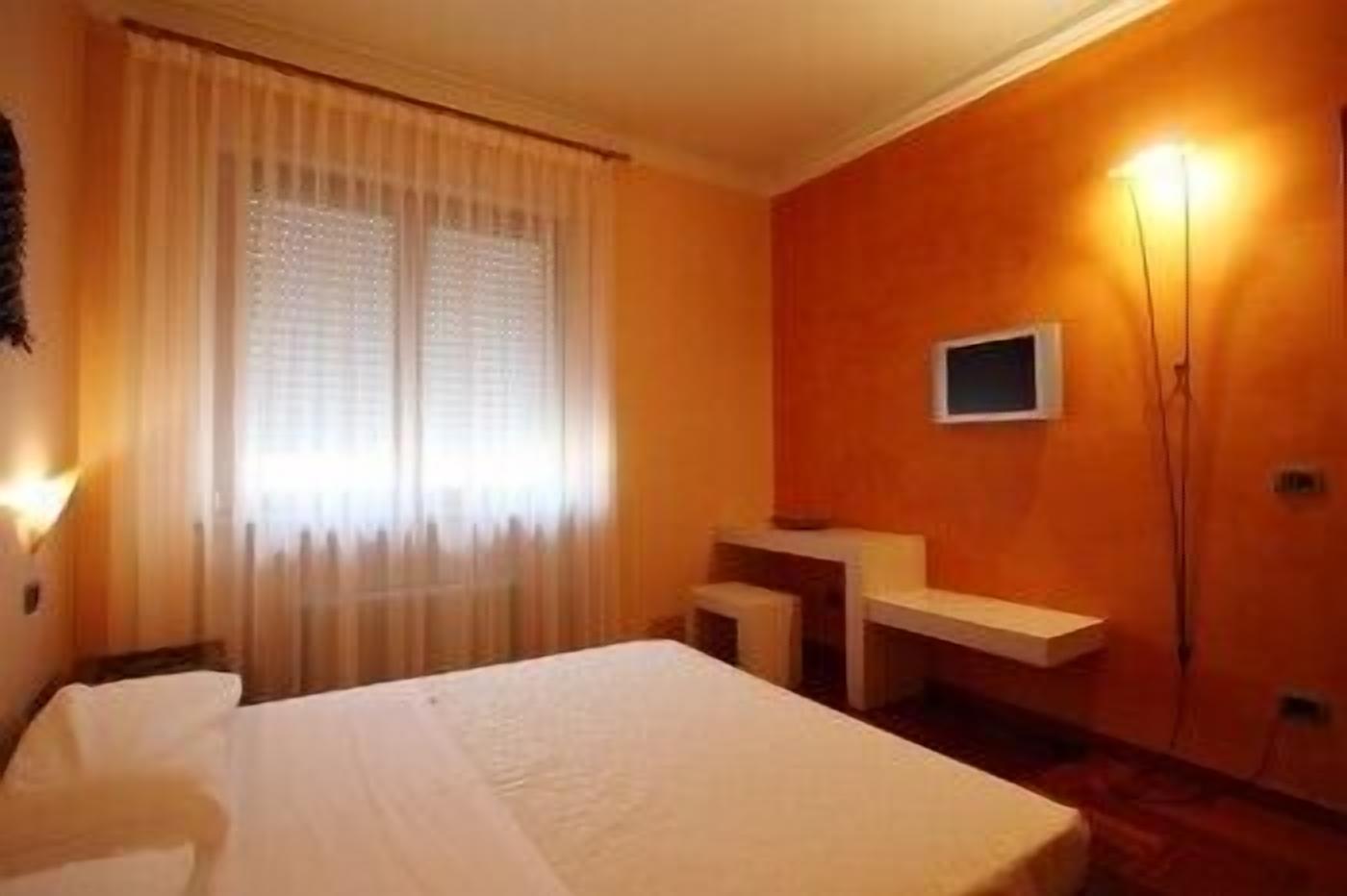 Una habitación de hotel con cama, escritorio y televisor montado en la pared.