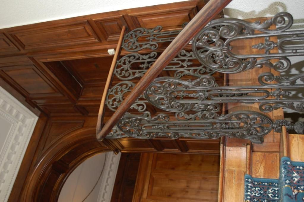 A wooden staircase with ornate metal railings.