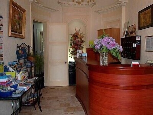 A reception area with a wooden desk, a vase of flowers, and a wall-mounted telephone.