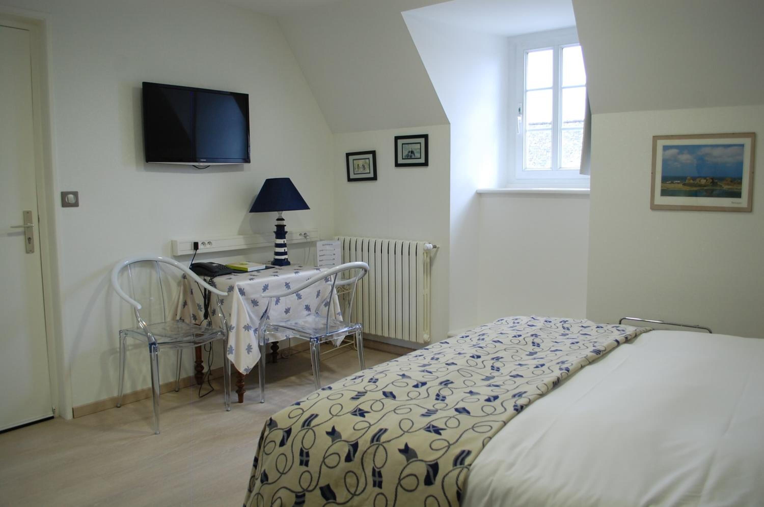 Una habitación con una cama, un escritorio con silla, televisión y ventana.