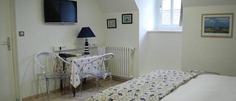 Una habitación con una cama, un escritorio con silla, televisión y ventana.