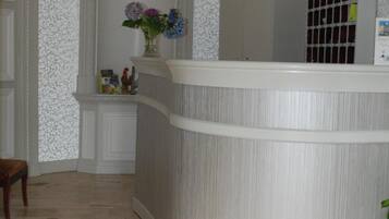 A reception area with a curved white counter, a vase with flowers, and framed photos on the wall.