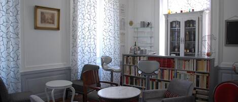 Une bibliothèque avec des étagères, un lustre et une cheminée.