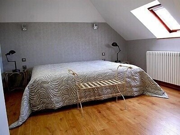 A small, single-bed room with a sloped ceiling and a skylight. There is a radiator on the wall and two bedside lamps. - Hôtel de l'Europe (Pontivy)