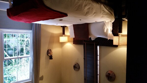 Una habitación con una cama, un ventanal y dos elementos decorativos en la pared.