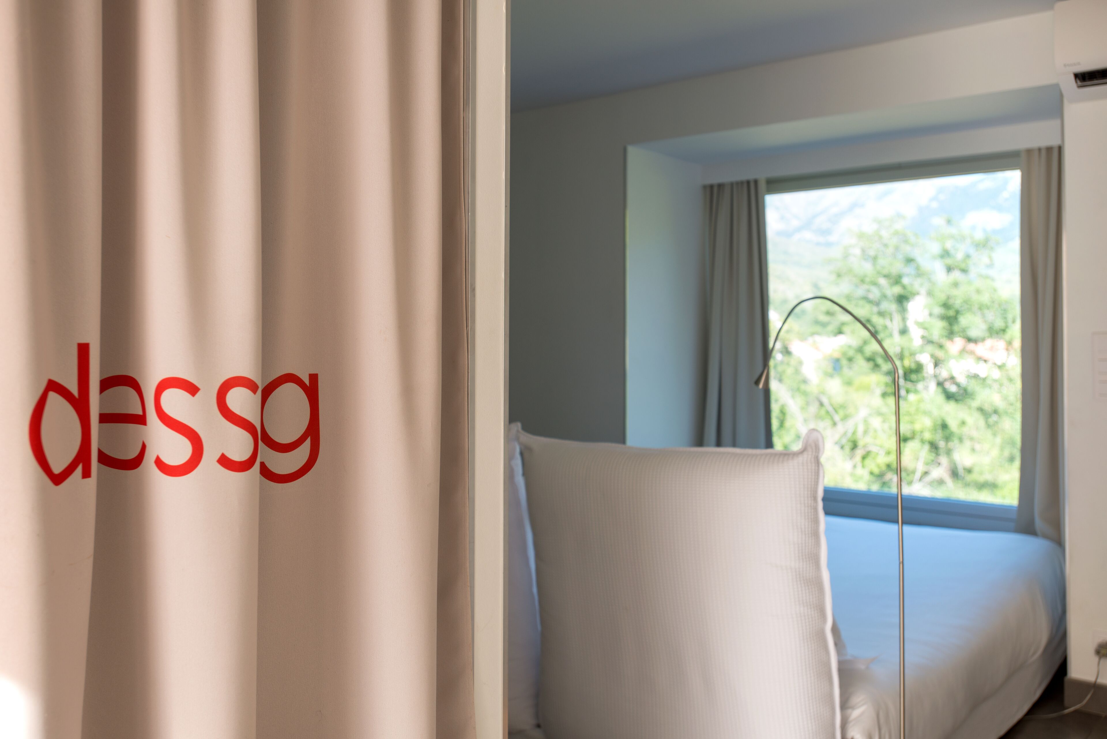 Een hotelkamer met een bed, een stoel en een raam met gordijnen.