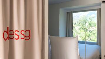 Een hotelkamer met een bed, een stoel en een raam met gordijnen.