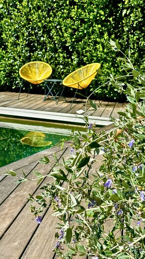 A wooden deck with a pool, surrounded by greenery and yellow chairs. - Artemisia Boutique Hôtel (Bastelica)