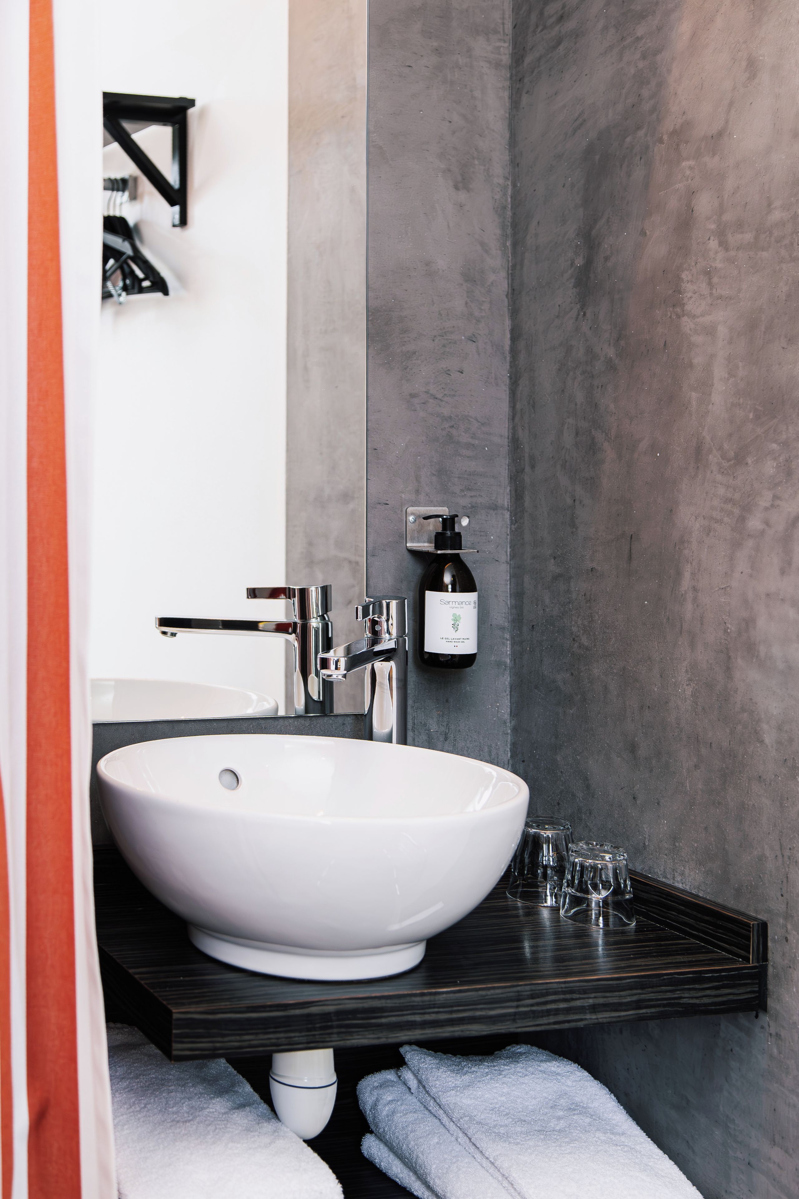Un baño moderno con un lavamanos blanco grande, grifos cromados y una encimera oscura.