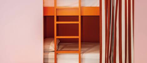 Dormitorio con literas, una escalera, un taburete pequeño naranja y una cortina.