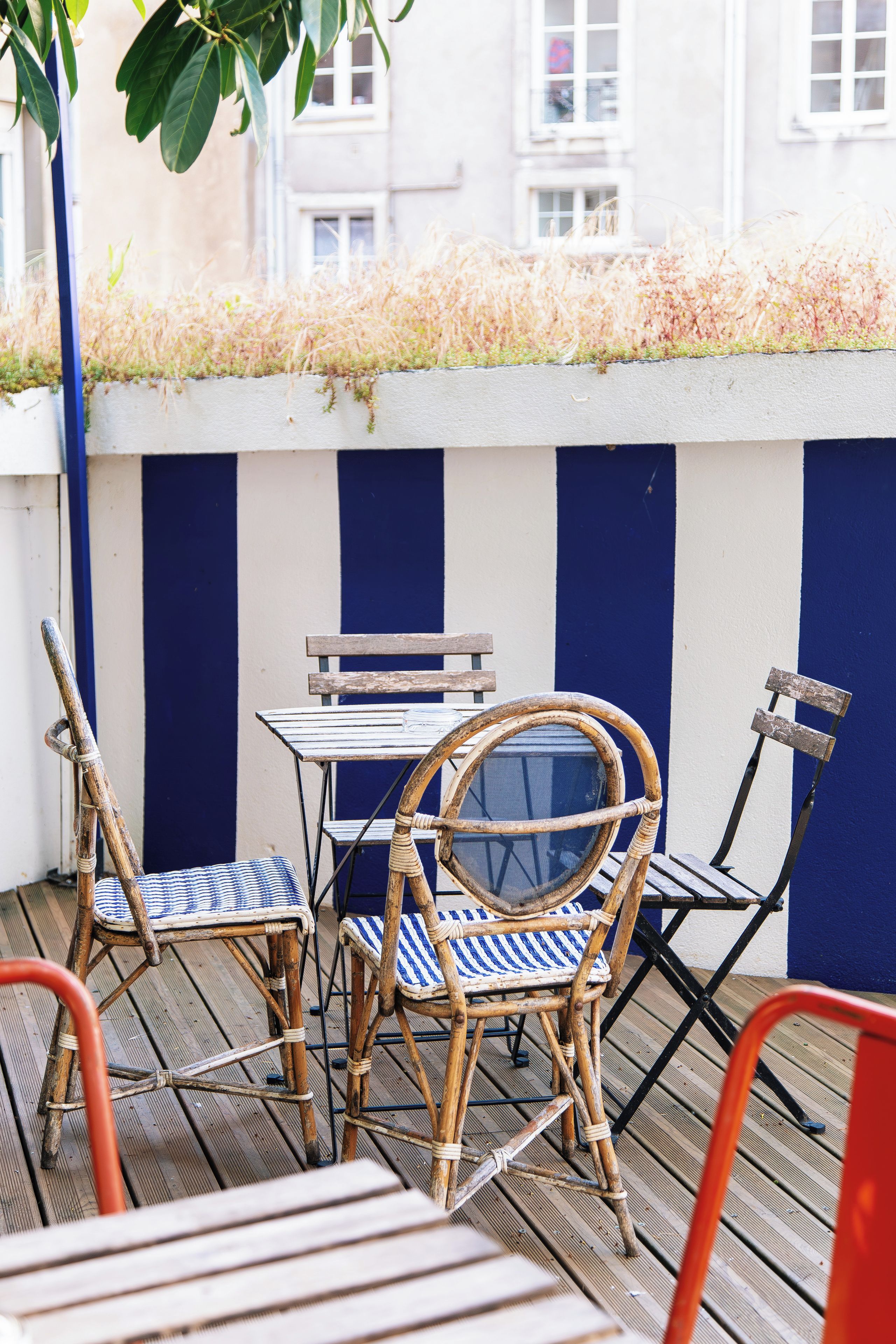 Una terrazza con mobili in vimini e un muro a righe.