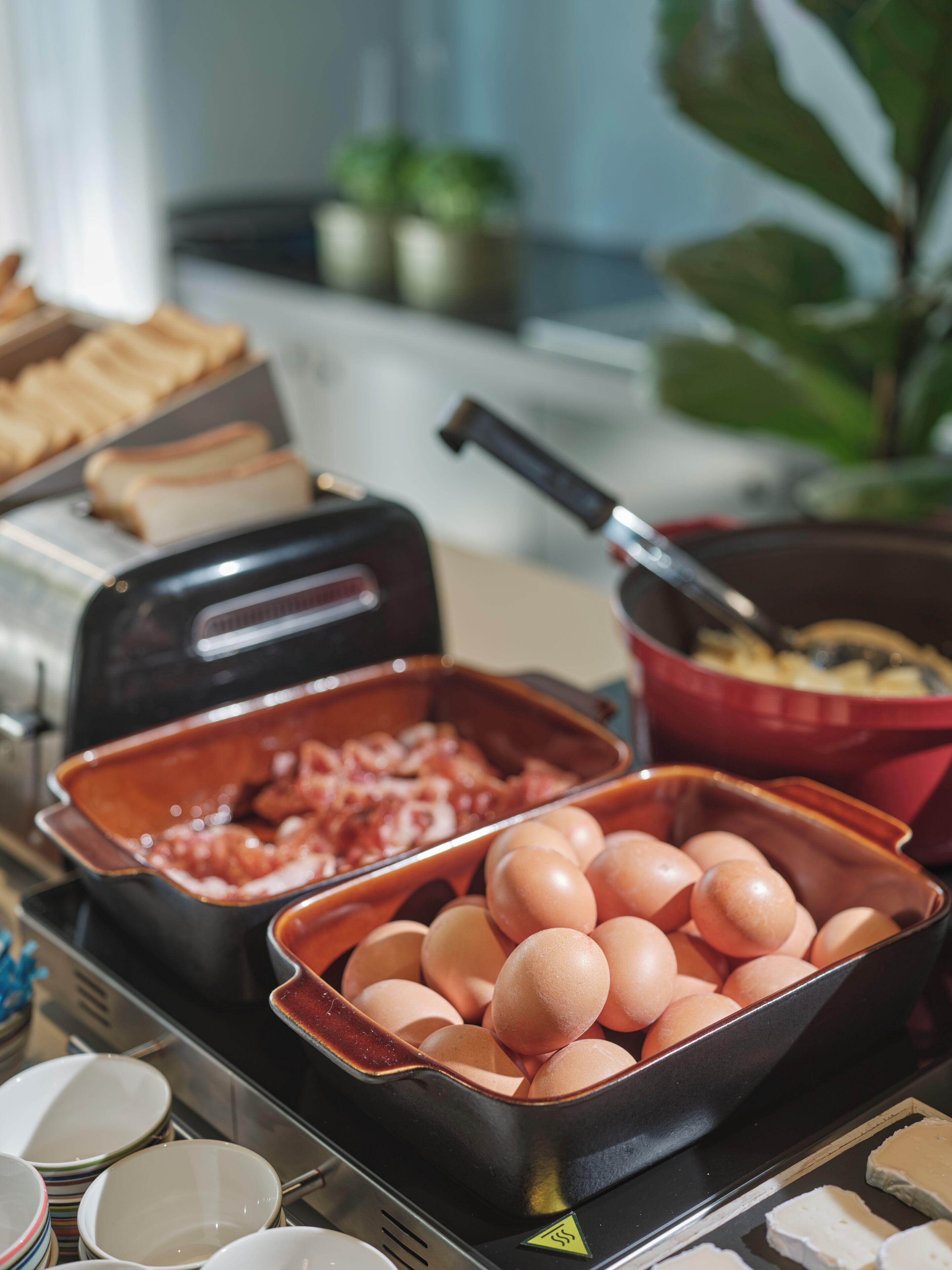 Un buffet proposant une variété d’aliments, notamment des œufs, du bacon et du pain.