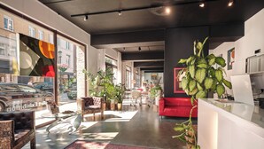 Een modern interieur met een rode bank, een glazen salontafel en potplanten.