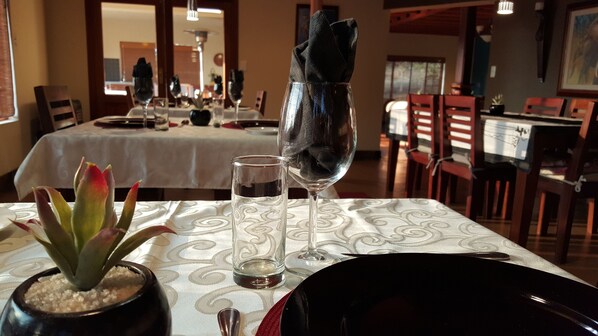 A dining table with a vase of flowers, a glass of water, and a wine glass with a napkin.
