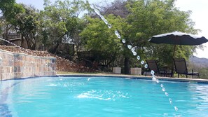 Una piscina al aire libre, sombrillas, sillones reclinables de piscina