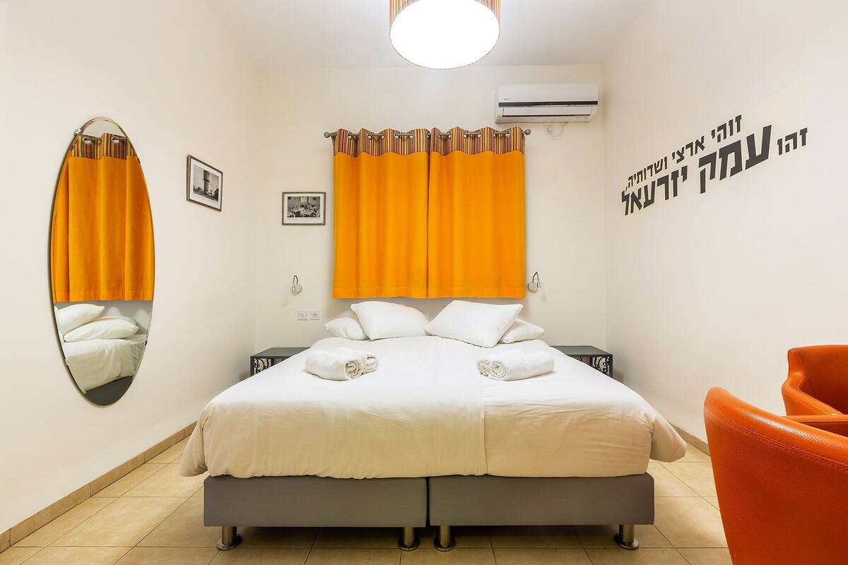 Une chambre à coucher avec un lit, un miroir, un climatiseur et une chaise.