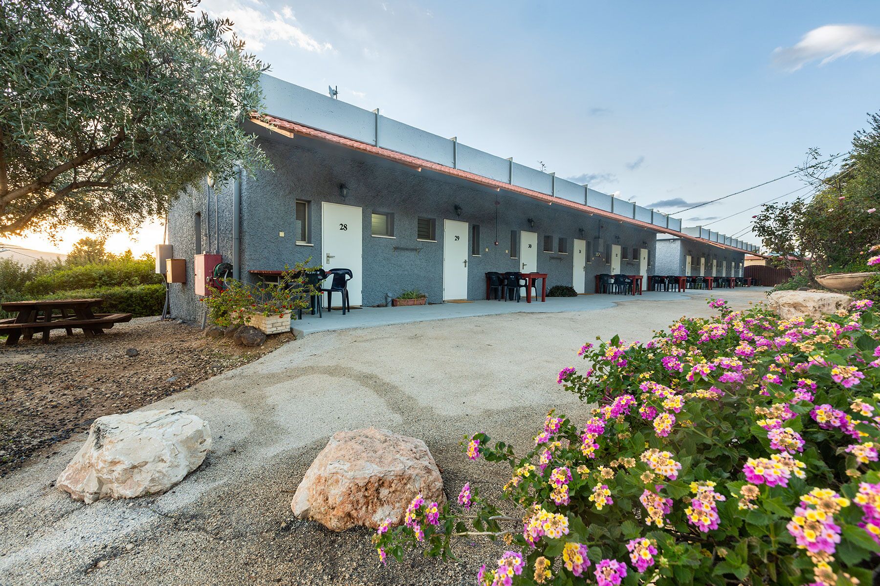 A building with numbered doors, outdoor seating, and a gravel path.