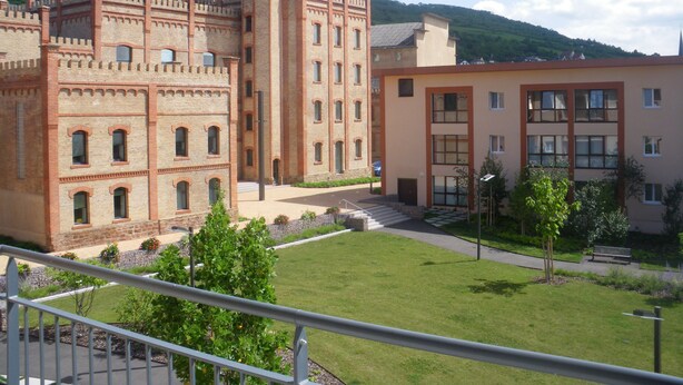 Un patio con un edificio de estilo castillo y una construcción moderna con ventanas grandes.