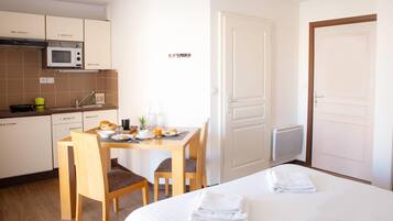 Een hotelkamer met een bed, een eettafel met stoelen, een magnetron en een kitchenette.