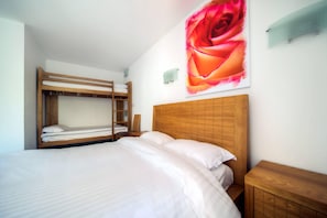 Un dormitorio con una cama nido, cabecera de madera, un cuadro grande de una rosa y una mesita de noche.