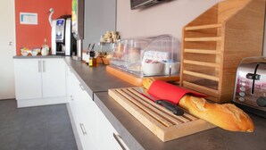 Una cocina con tabla de madera, pan, tostadora y microondas.