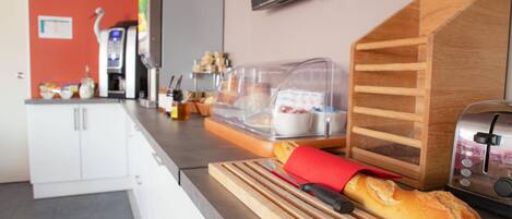 Une cuisine avec une planche à découper en bois, une miche de pain, un grille-pain et un four à micro-ondes.
