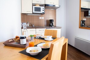 Frühstücksaufstellung mit Tablett, Marmeladenglas, Orangensaftglas, Müslischüssel und Teller mit Brot und Tasse.