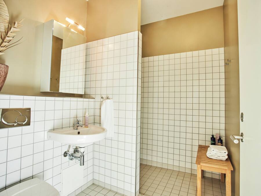 A bathroom with a white sink, mirror, and tiled walls.