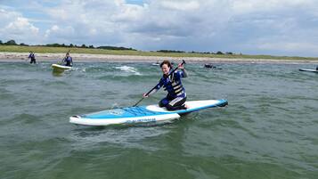A person on a paddleboard in a body of water with other paddleboarders in the background.