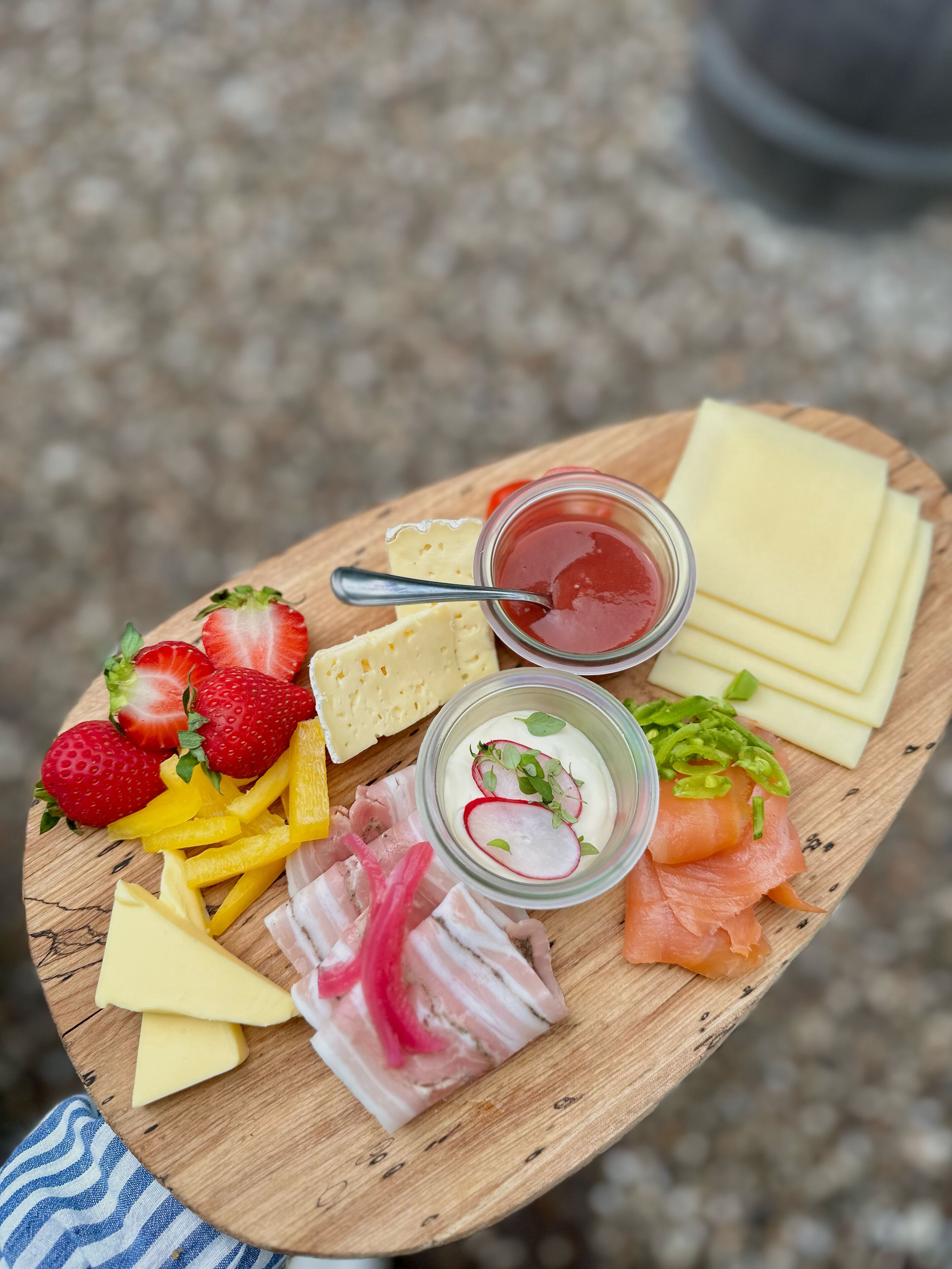 Ein Holzbrett mit verschiedenen Speisen, darunter Käse, Erdbeeren, Radieschen und Räucherlachs.