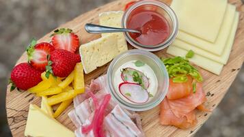 Ein Holzbrett mit verschiedenen Speisen, darunter Käse, Erdbeeren, Radieschen und Räucherlachs.