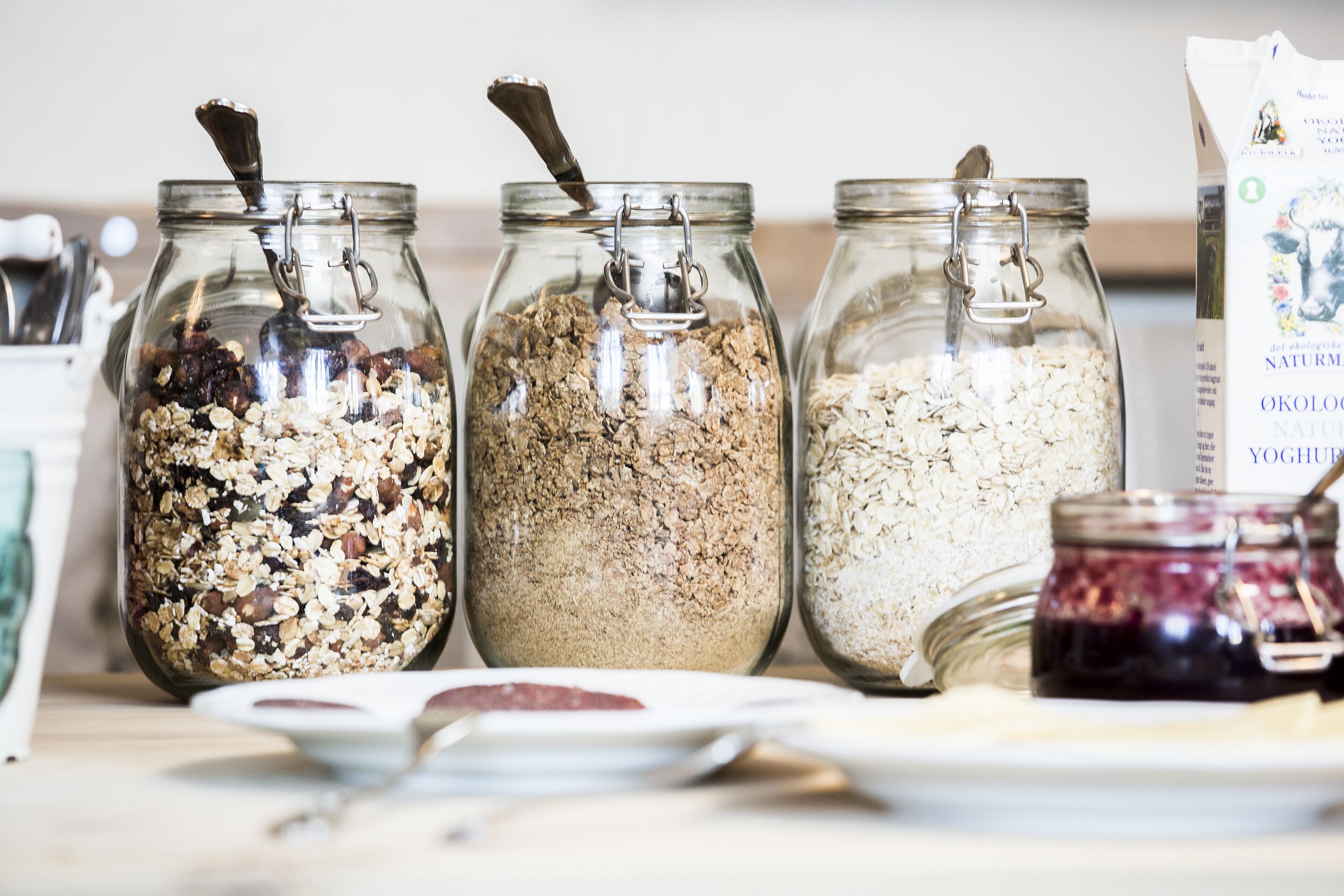 Tres frascos de vidrio con cierres metálicos que contienen distintos tipos de granola sobre una mesa.