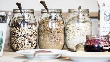 Tres frascos de vidrio con cierres metálicos que contienen distintos tipos de granola sobre una mesa.