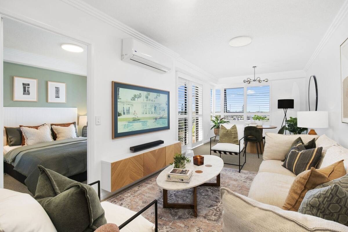 A modern living room with a bed, sofa, coffee table, and artwork.