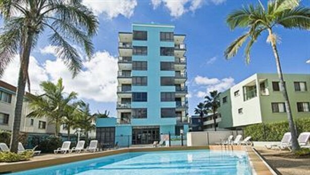 A hotel with a swimming pool, palm trees, and a multi-story building with balconies. - Aqualine Apartments (Southport)