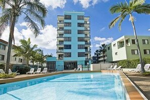 A hotel with a swimming pool, palm trees, and a multi-story building with balconies. - Aqualine Apartments (Southport)