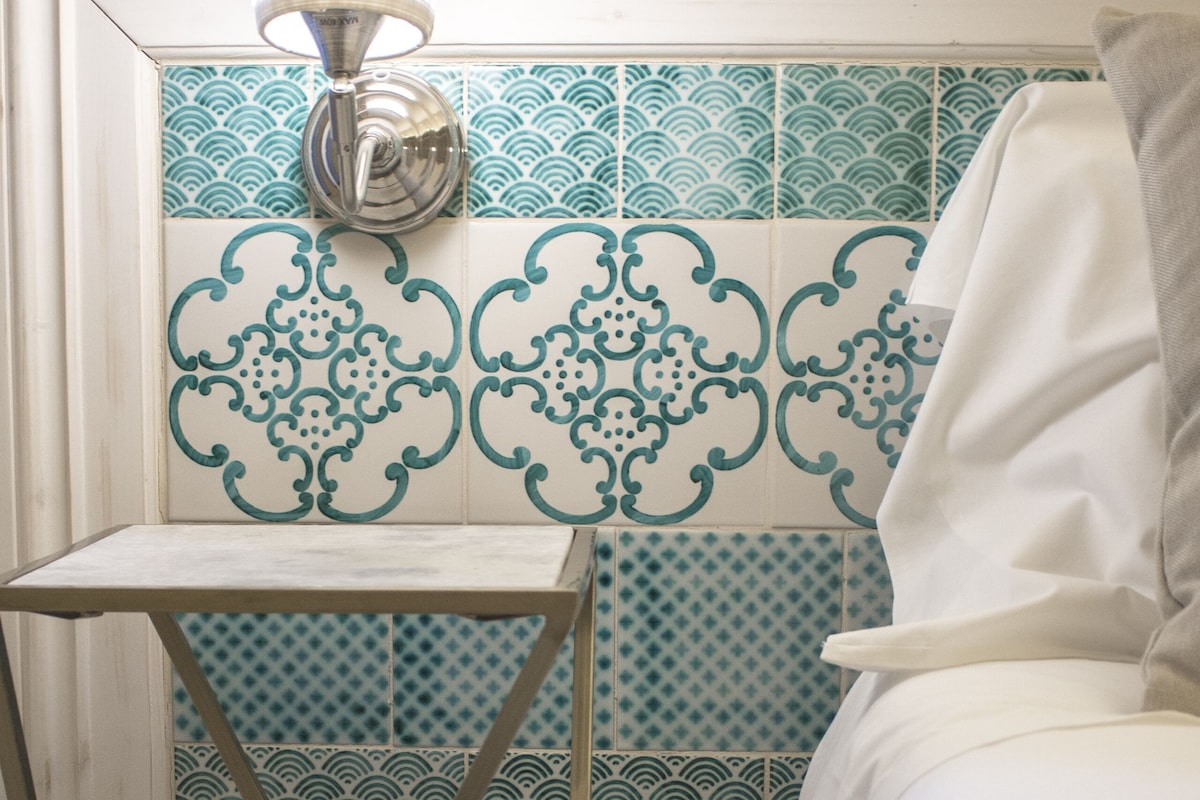 Un baño con lavamanos blanco, toallero y salpicadero de azulejos con diseño.