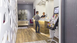 Un área de recepción de diseño moderno, con mostrador de recepción, zona de estar con sofá y sillones, y una pared decorativa con patrones recortados.