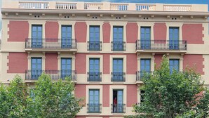 Un edificio de varios pisos con fachada simétrica, con ventanas y balcones uniformemente distribuidos y barandales negros.