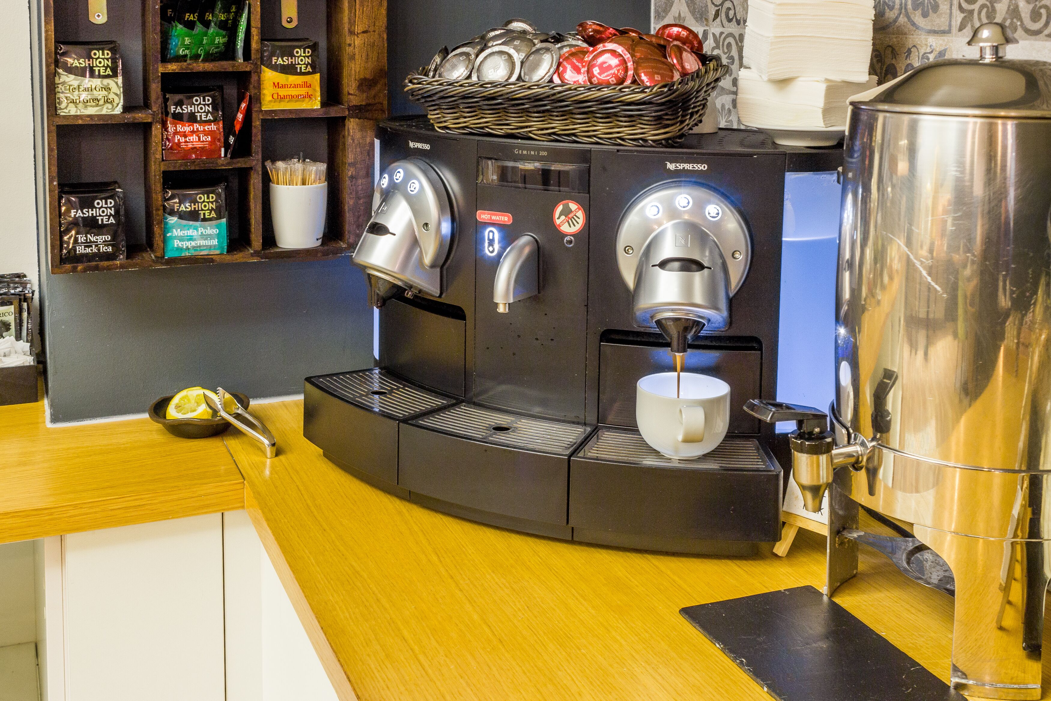 Una macchina da caffè con due erogatori e un cestino di tazze sopra.