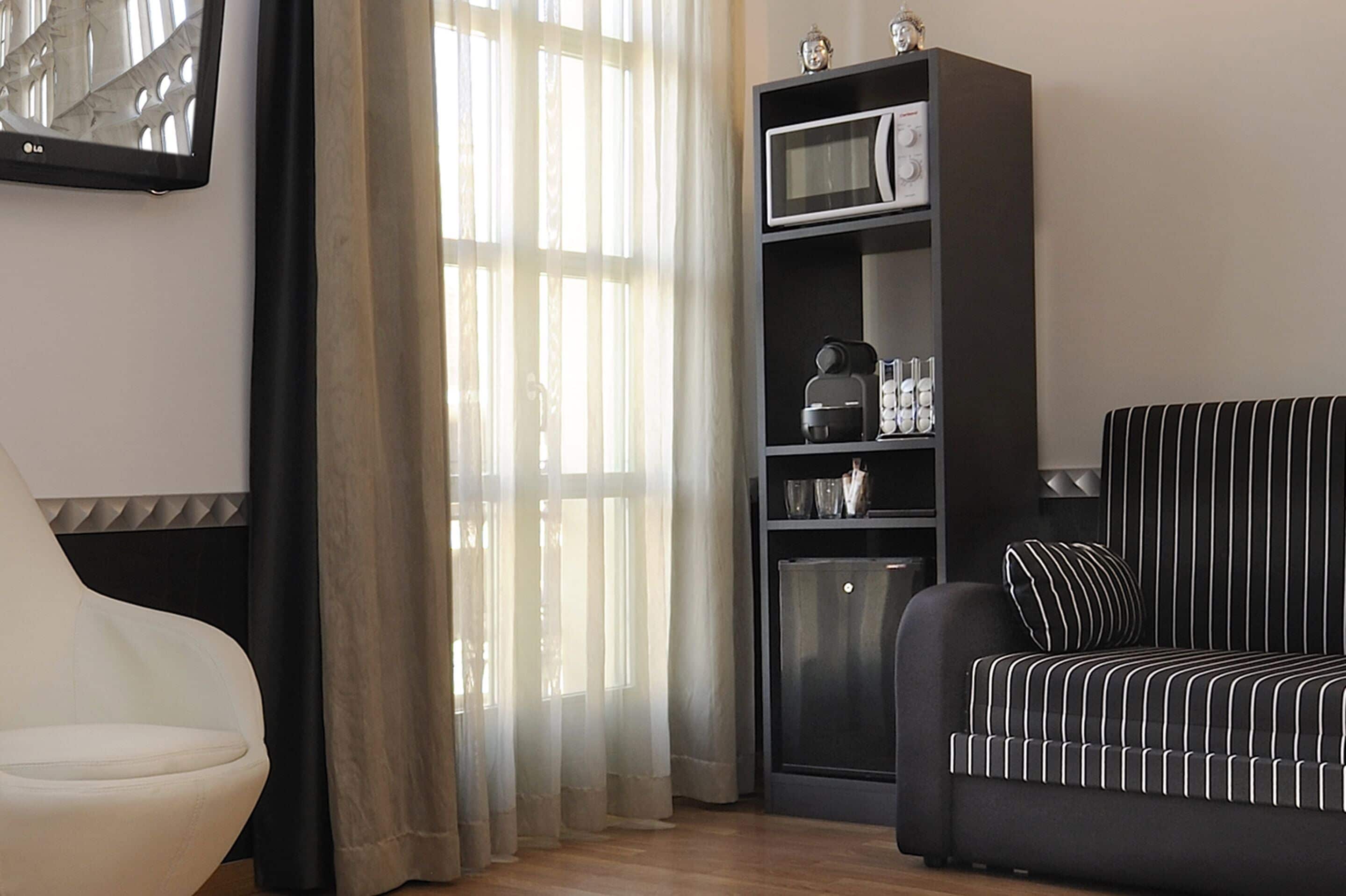 A modern living room with a sofa, a chair, a bookshelf, and a refrigerator.