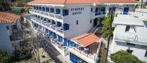 Un hotel con techo de tejas rojas, varios balcones y un letrero que dice "ATHERAS HOTEL".