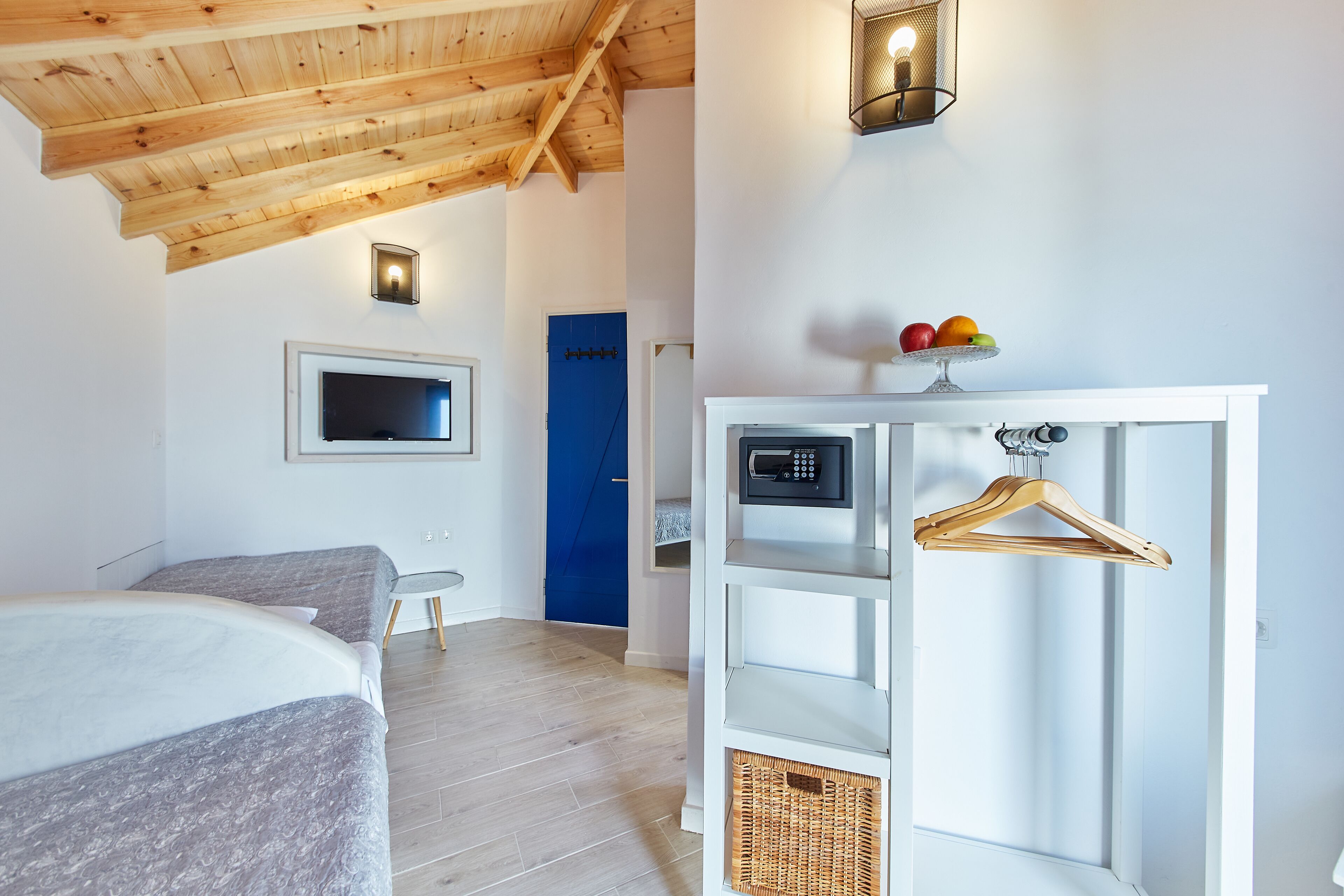 Un dormitorio con una cama, televisión, armario y una puerta azul.