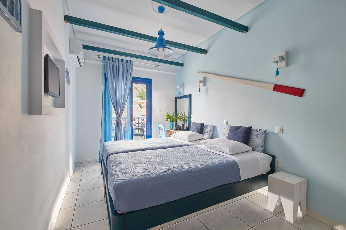 A bedroom with two beds, a ceiling fan, a TV, and a window with curtains.
