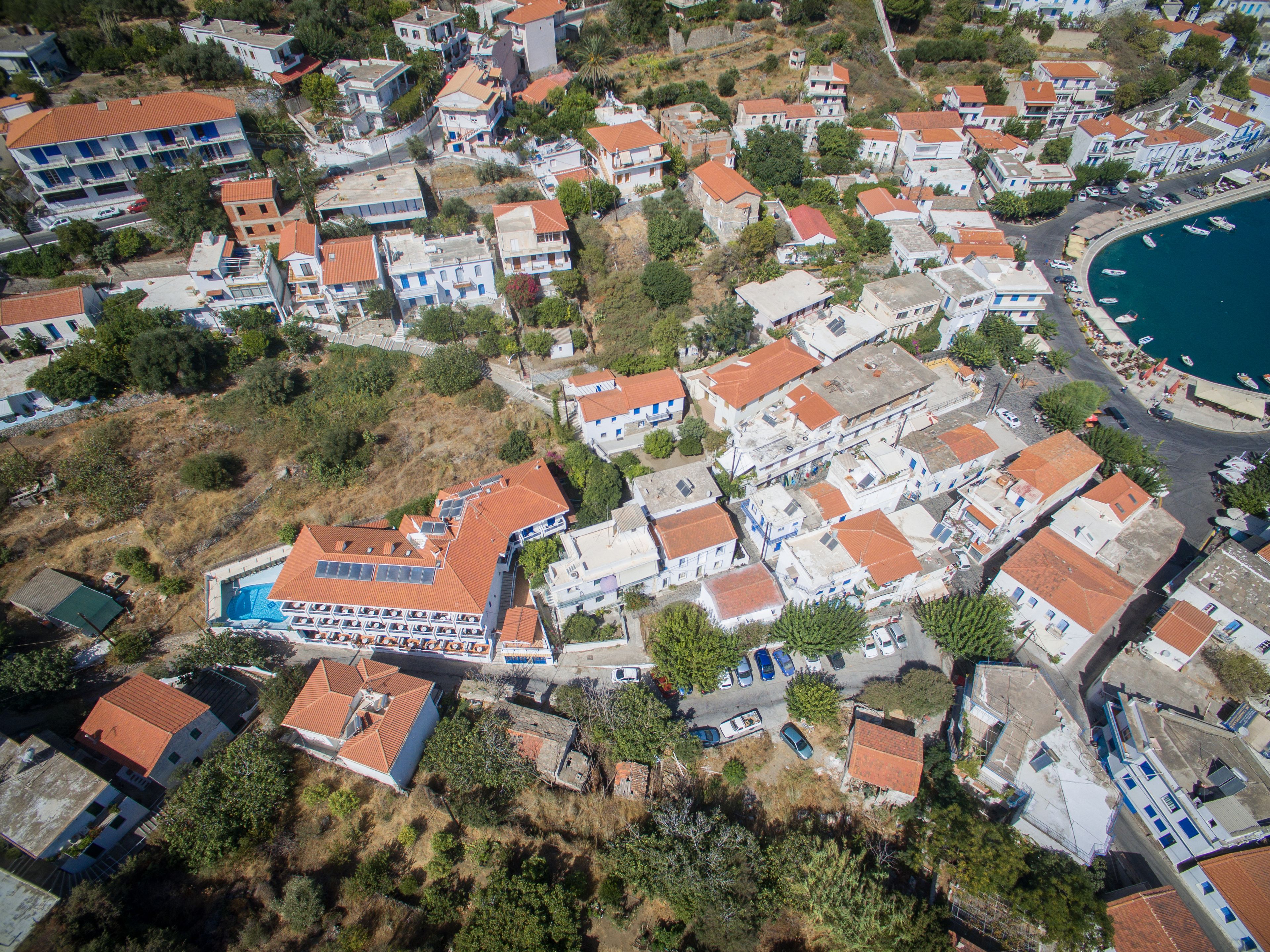 An aerial view of a coastal residential area with a mix of single and multi-story buildings, a marina with boats, and a swimming pool complex.