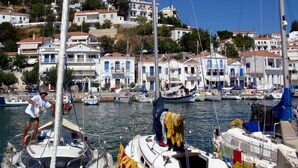 A marina with multiple sailboats docked, surrounded by buildings with red-tiled roofs and white walls. - Atheras (Ikaria)