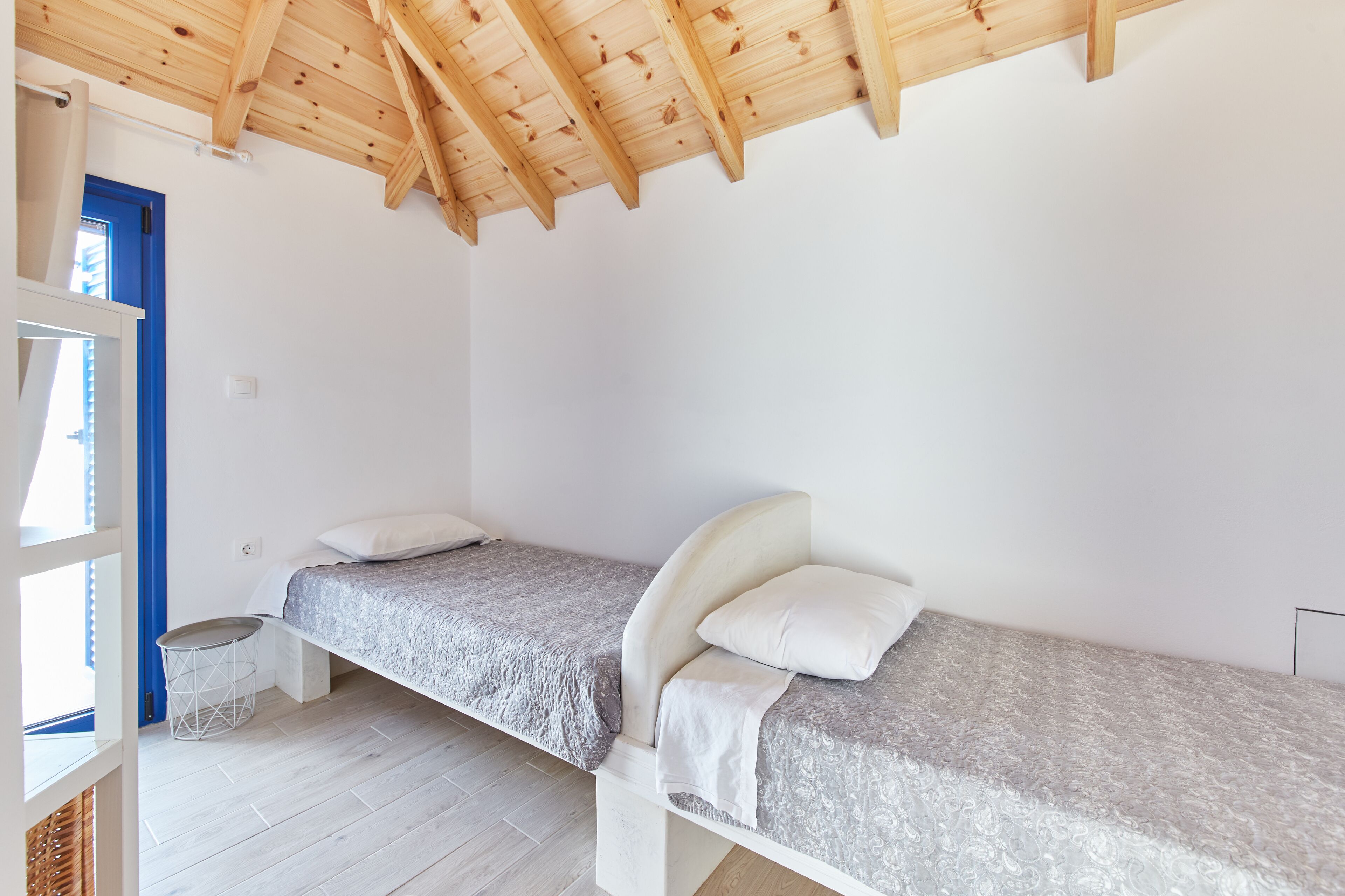Un dormitorio con dos camas individuales, techo de madera y pared blanca.